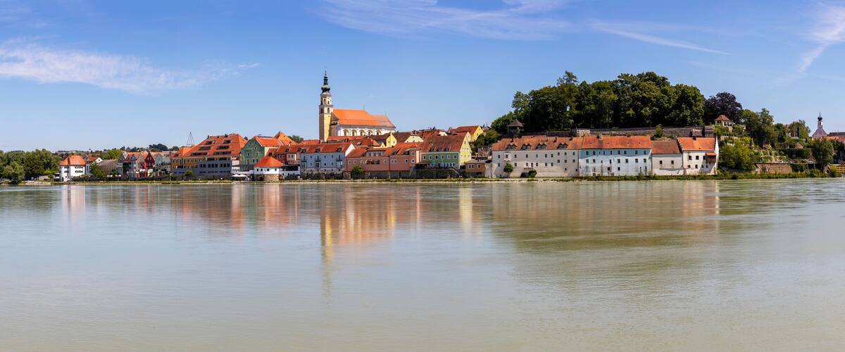 A riverside town with historic buildings, a prominent church tower, and a bridge.