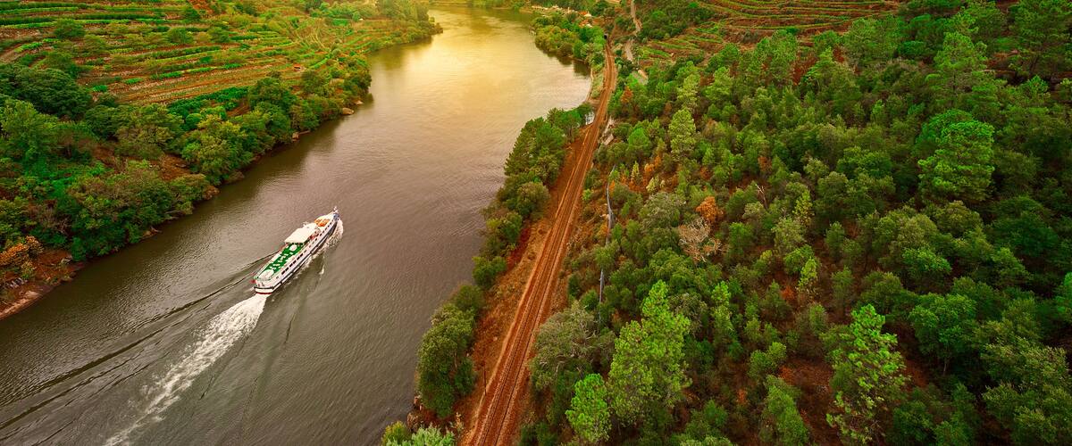 A river winding through a hilly landscape with lush greenery and a boat traveling along the water.