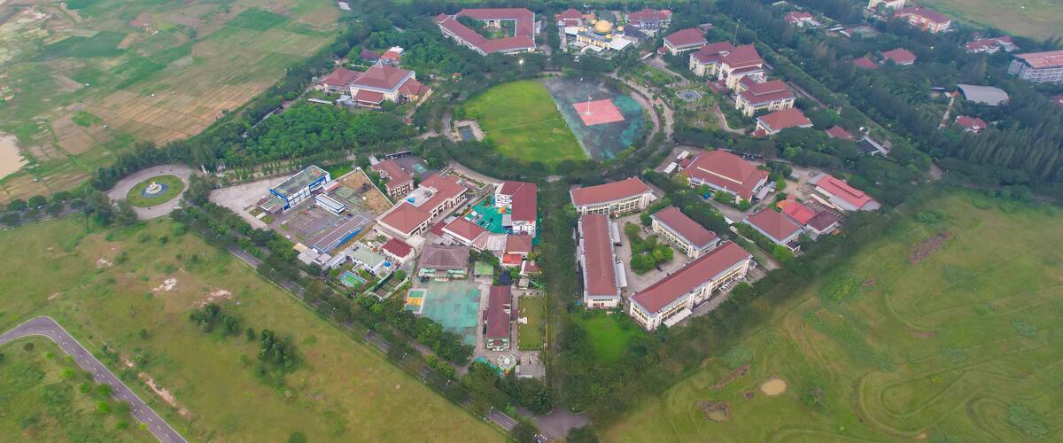 An aerial view of a residential area with houses, a central green space, and surrounding fields.