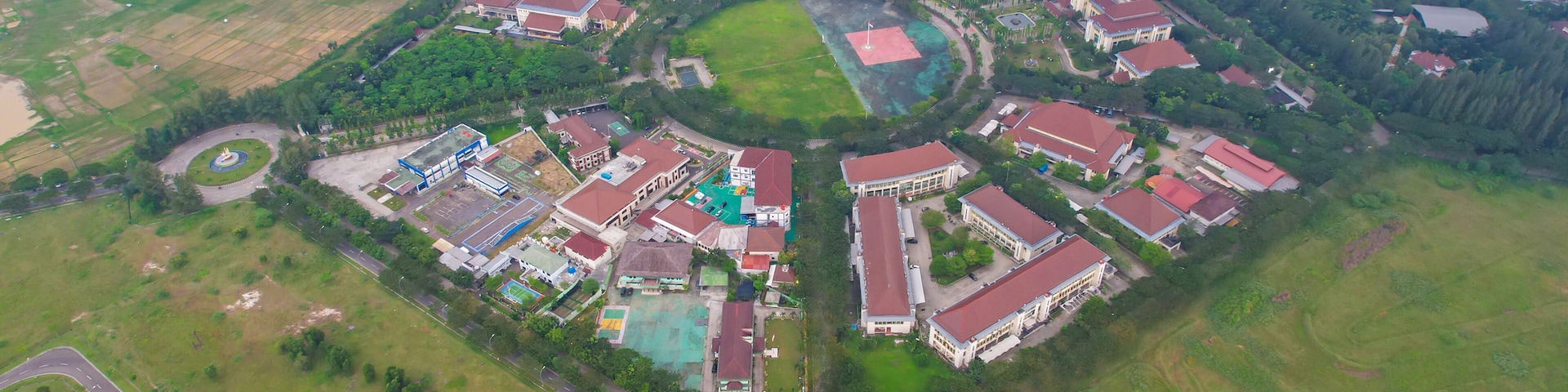 An aerial view of a residential area with houses, a central green space, and surrounding fields.