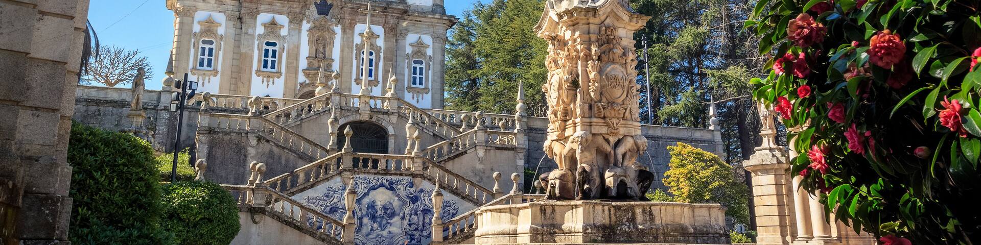 A historic building with ornate architecture, a prominent statue, and a decorative staircase.