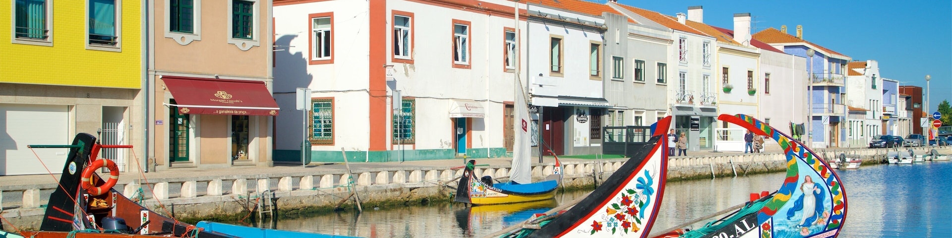 Barcos de colores amarrados a lo largo de una orilla, con edificios de estilo europeo al fondo.