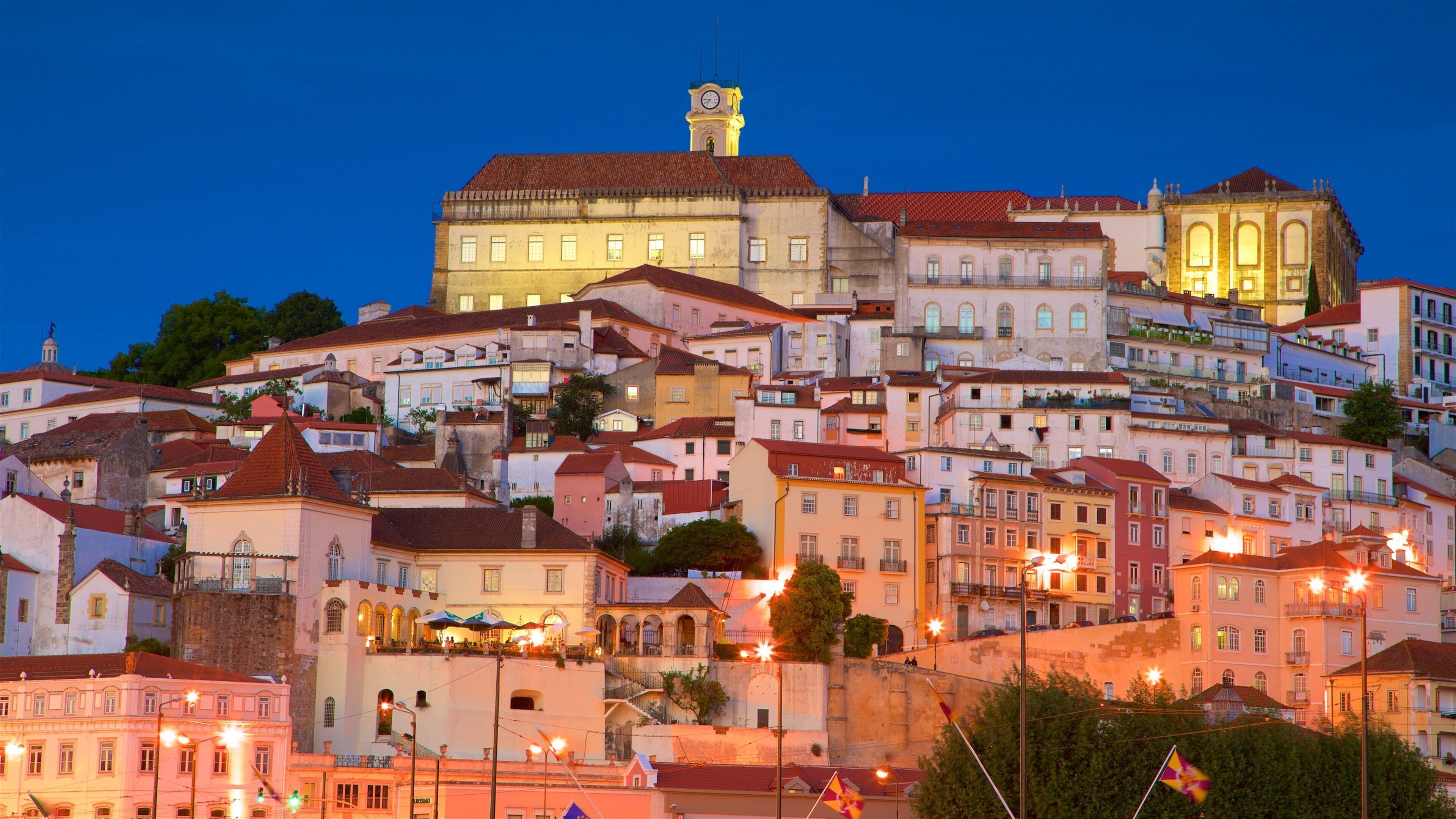A historic town with a prominent clock tower, colorful buildings, and a hillside layout.