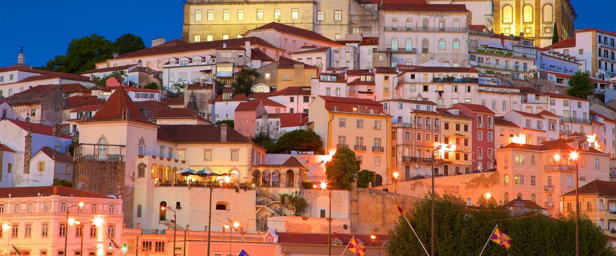 A historic town with a prominent clock tower, colorful buildings, and a hillside layout.