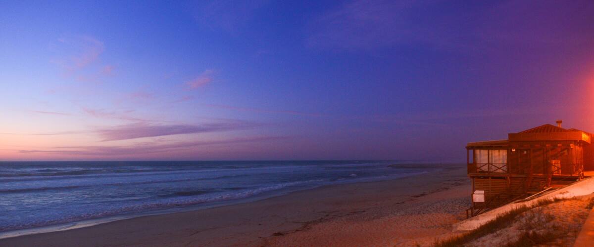 A beach with a lifeguard tower at sunset.