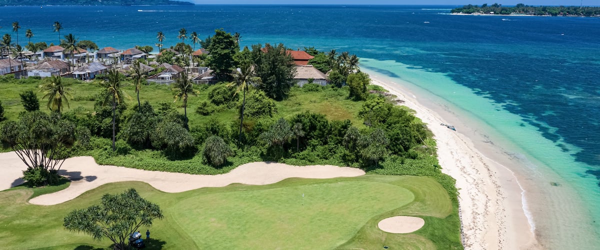 A coastal golf course with a beach and ocean.
