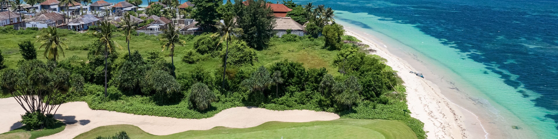 A coastal golf course with a beach and ocean.