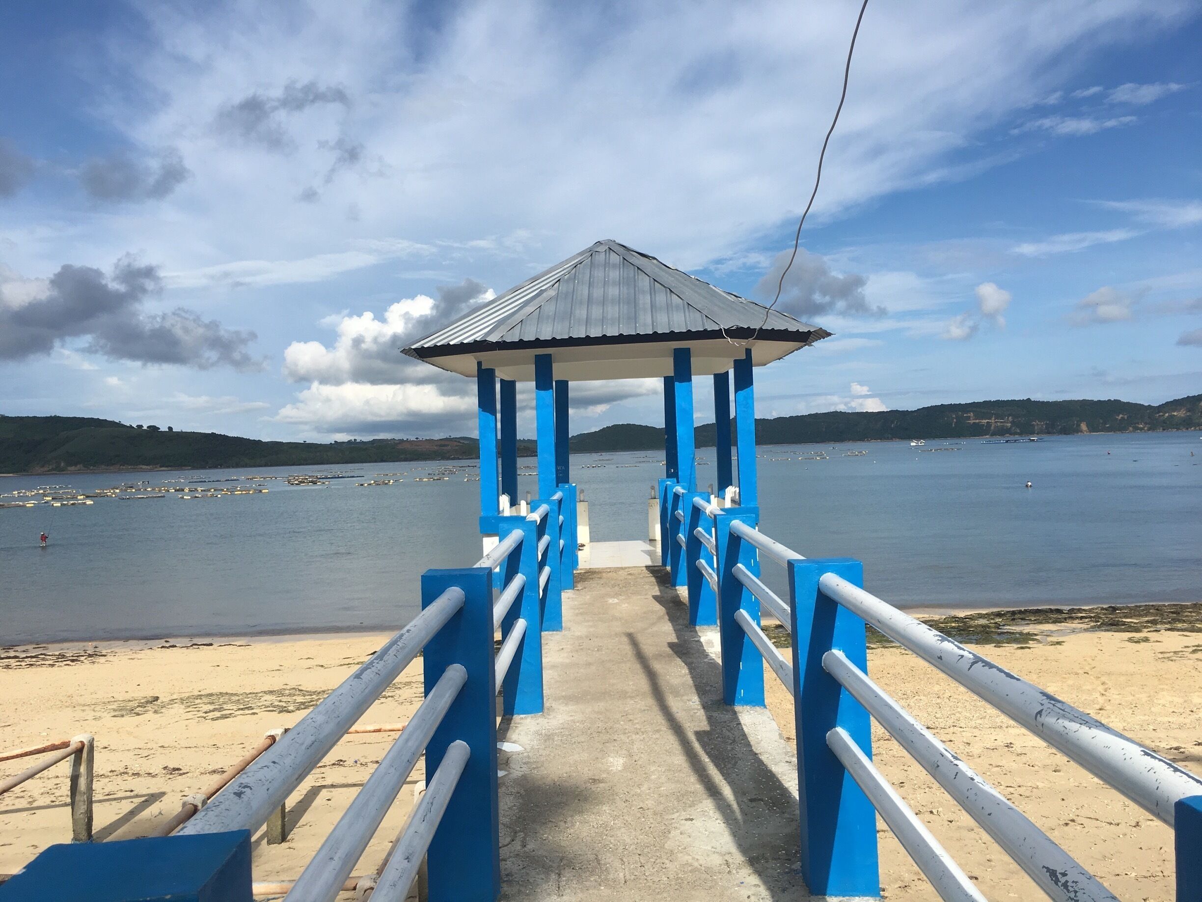 A pier with a blue and white structure leading to a body of water.