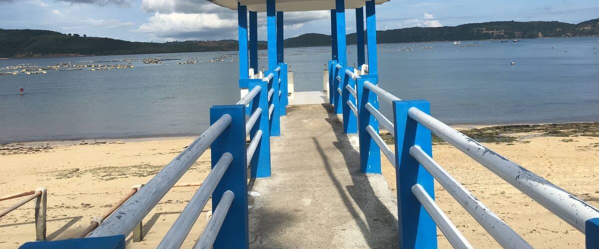 A pier with a blue and white structure leading to a body of water.