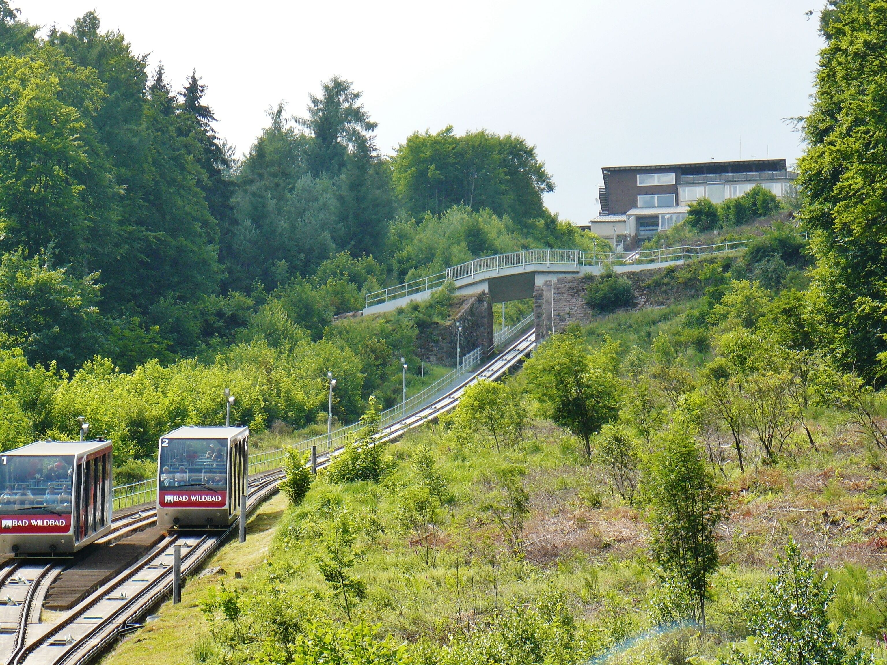A train on tracks with a bridge and a building in the background.