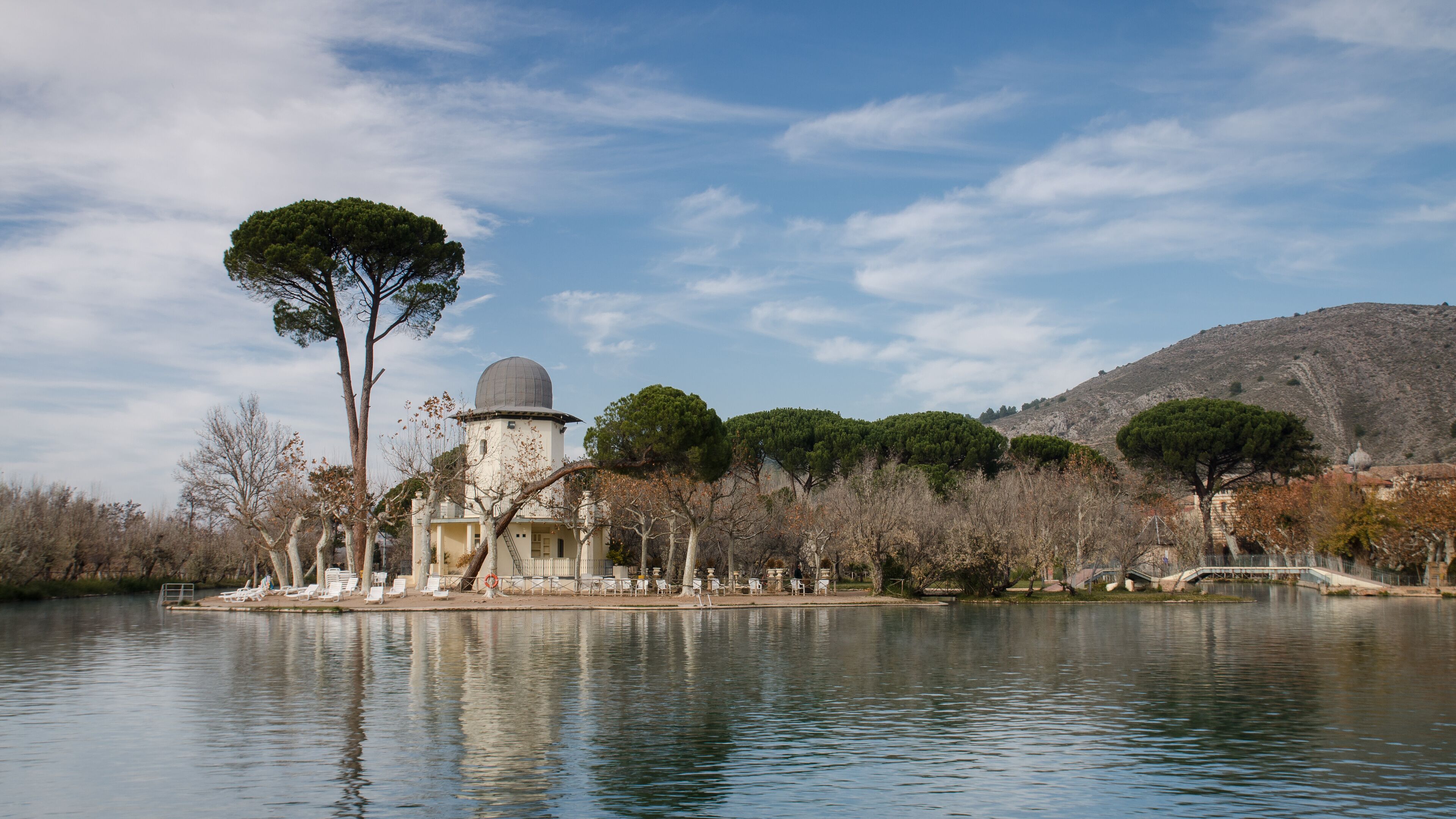 A lake with a small island featuring a building with a dome and trees.