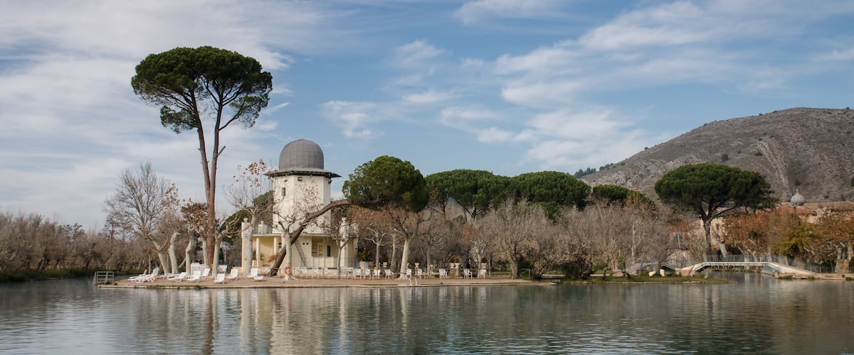 A lake with a small island featuring a building with a dome and trees.