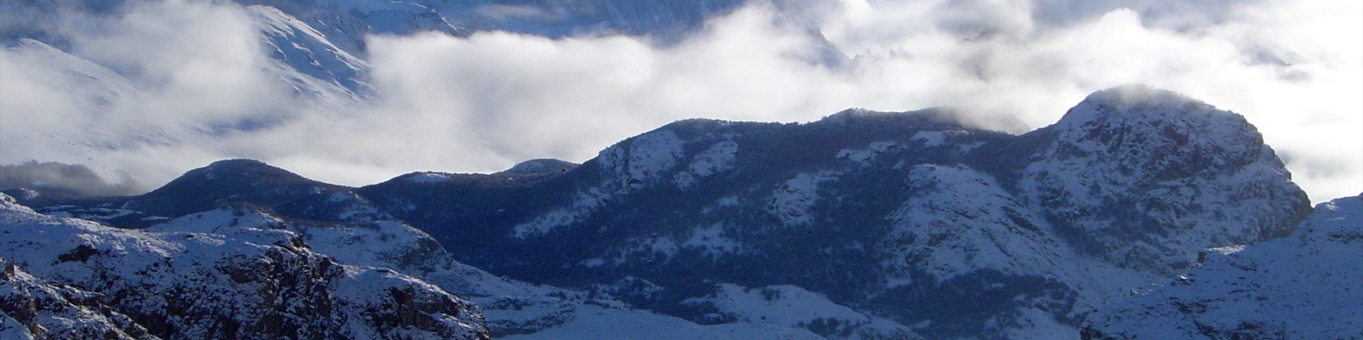 A snow-covered mountainous landscape with a prominent peak and a valley.