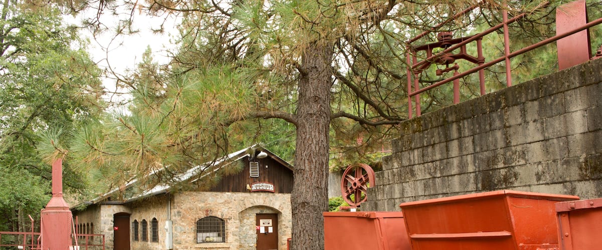 A rustic building labeled 'HUSBRU,' a red water wheel, and a red dump truck on tracks.