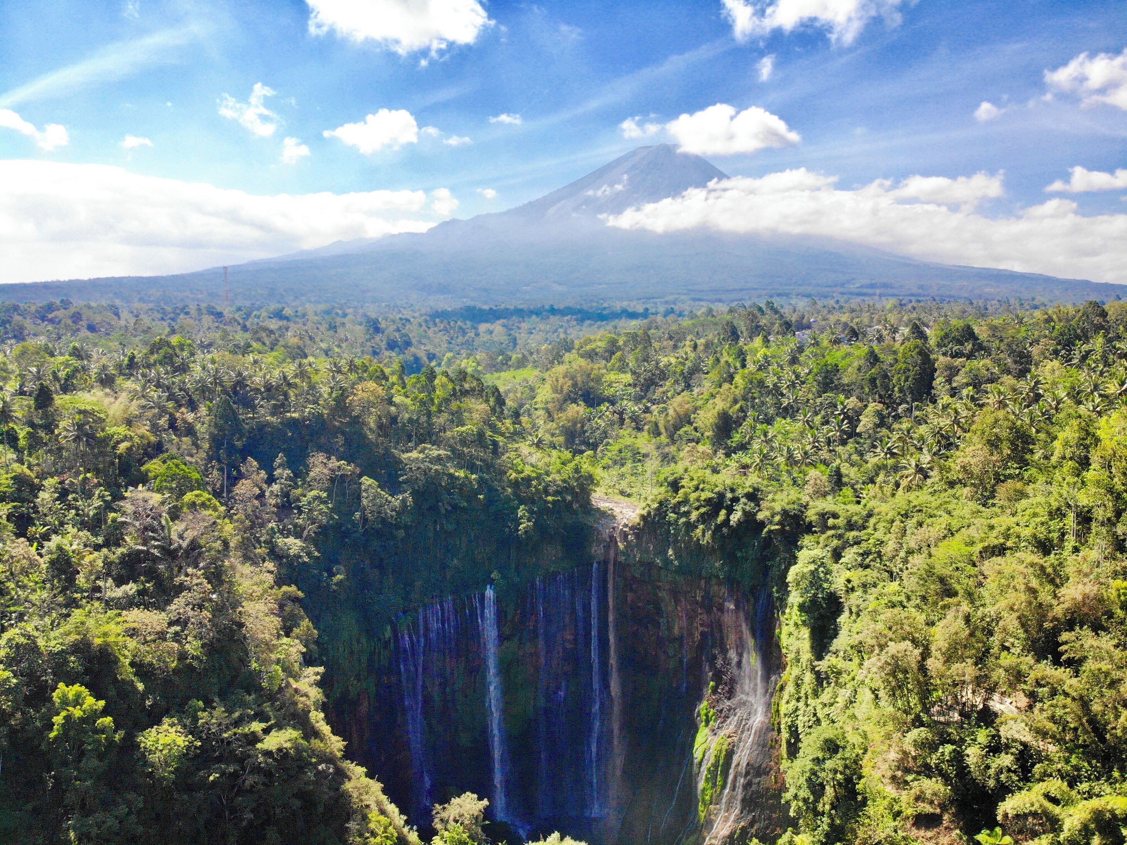 Drone shot where you can see the waterfall with Semeru Volcano behind