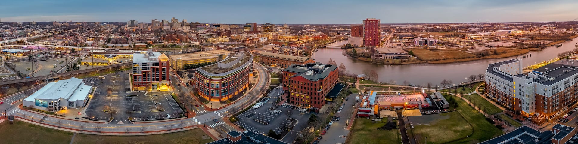 A cityscape with a river, modern buildings, and a highway interchange.