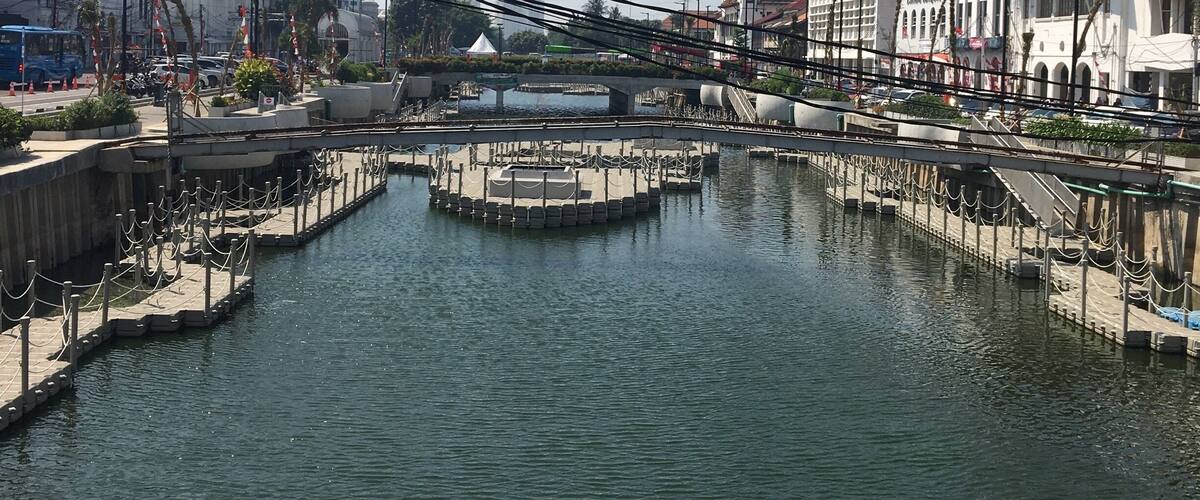A canal with a bridge, surrounded by buildings and a clear sky.