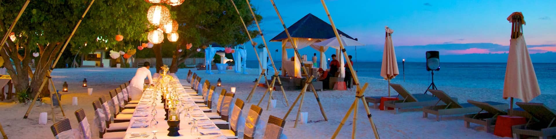 A beachside dining setup with tables and chairs, a canopy, and a beach in the background.