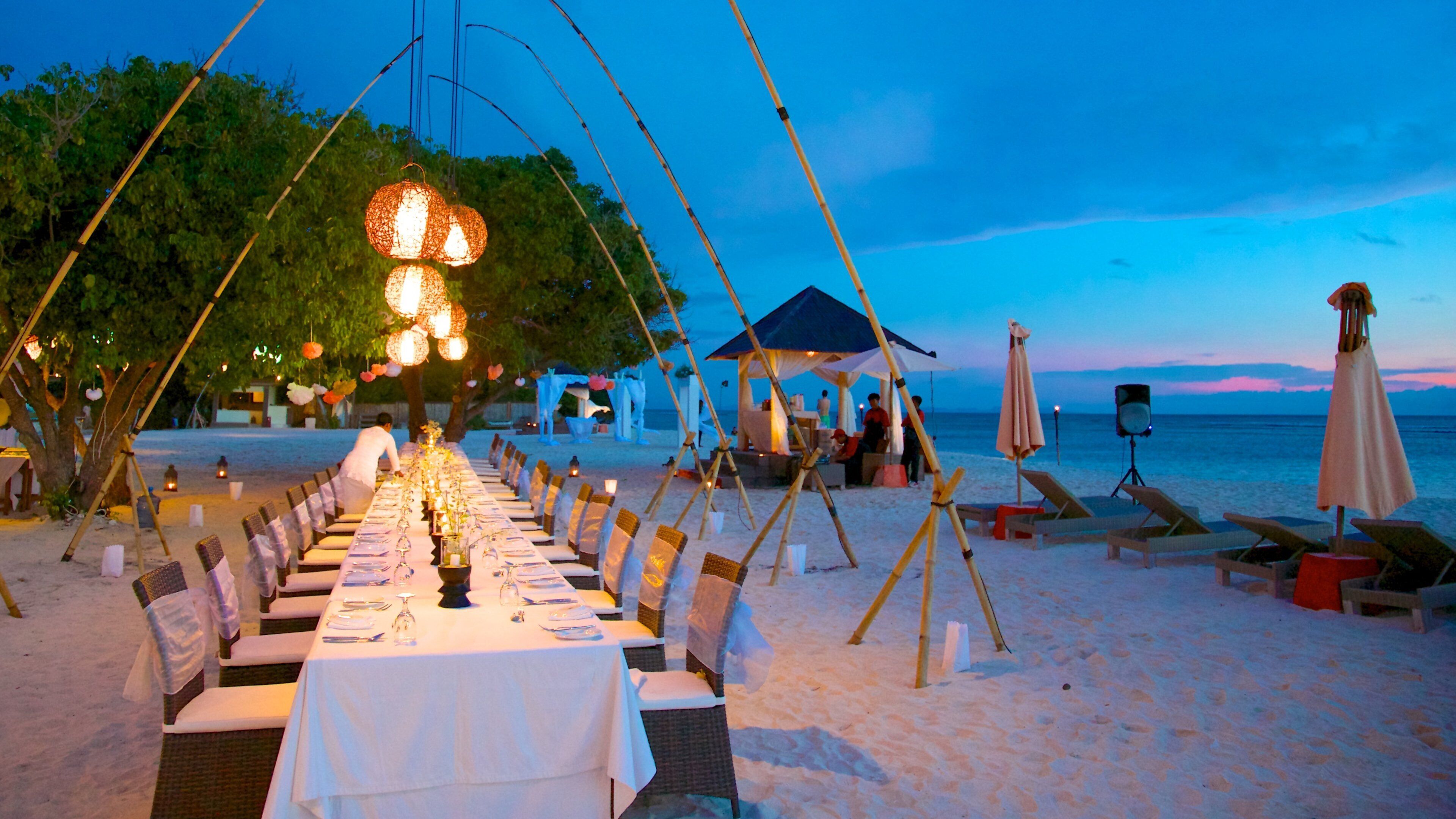 A beachside dining setup with tables and chairs, a canopy, and a beach in the background.