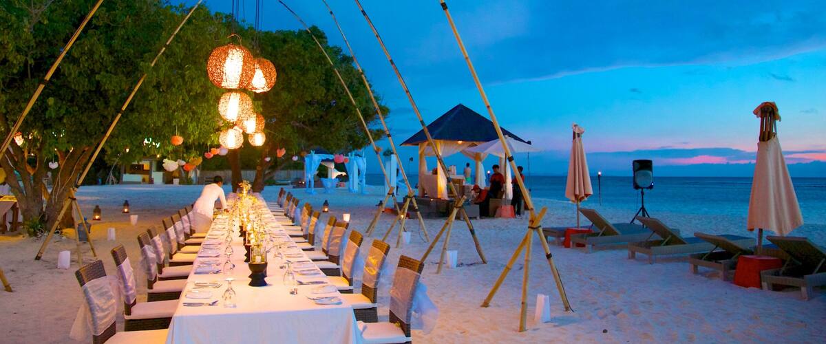 A beachside dining setup with tables and chairs, a canopy, and a beach in the background.