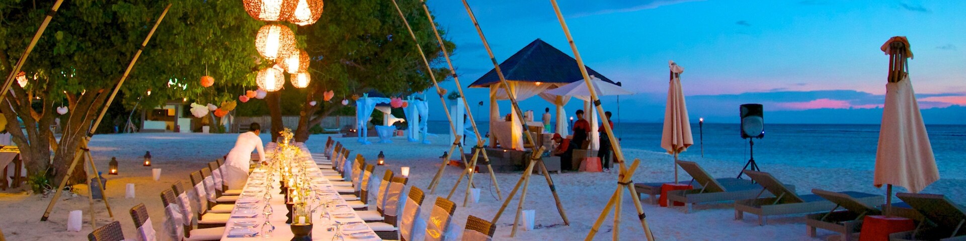 A beachside dining setup with tables and chairs, a canopy, and a beach in the background.