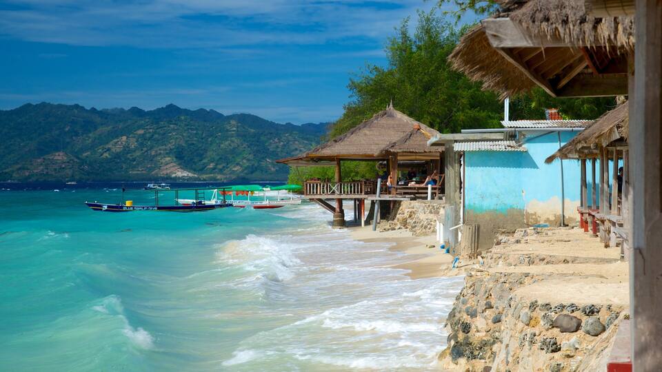A beach with clear turquoise water, wooden structures, and boats.