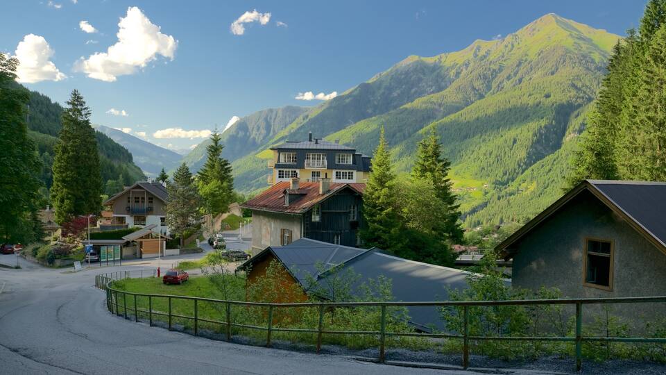A mountain village with houses, a road, and a forested valley.