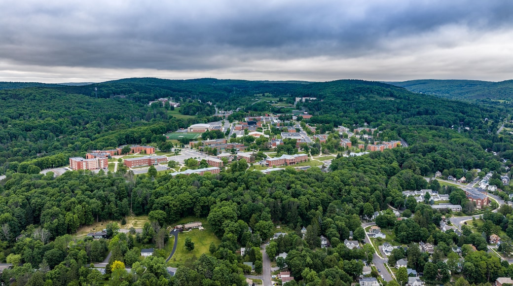 A campus with multiple buildings, surrounded by dense forests and rolling hills.