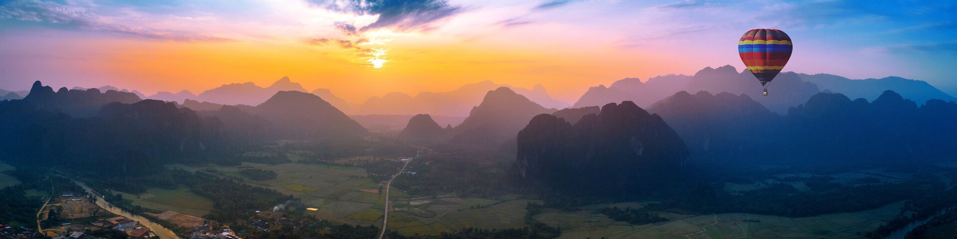 Aerial view of Vang vieng with mountains and balloon at sunset.