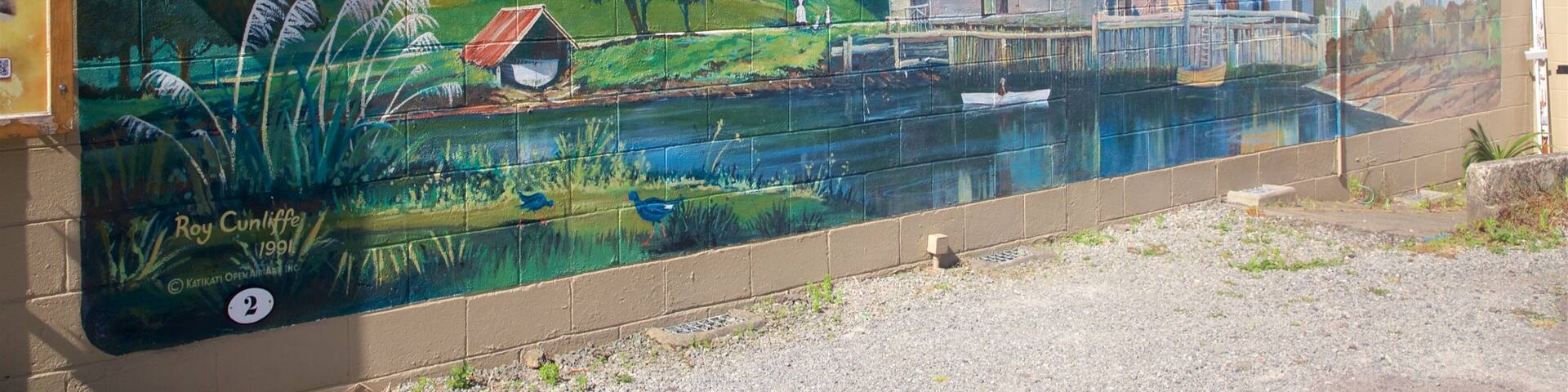 A mural of a rural landscape with houses, a river, and a boat.