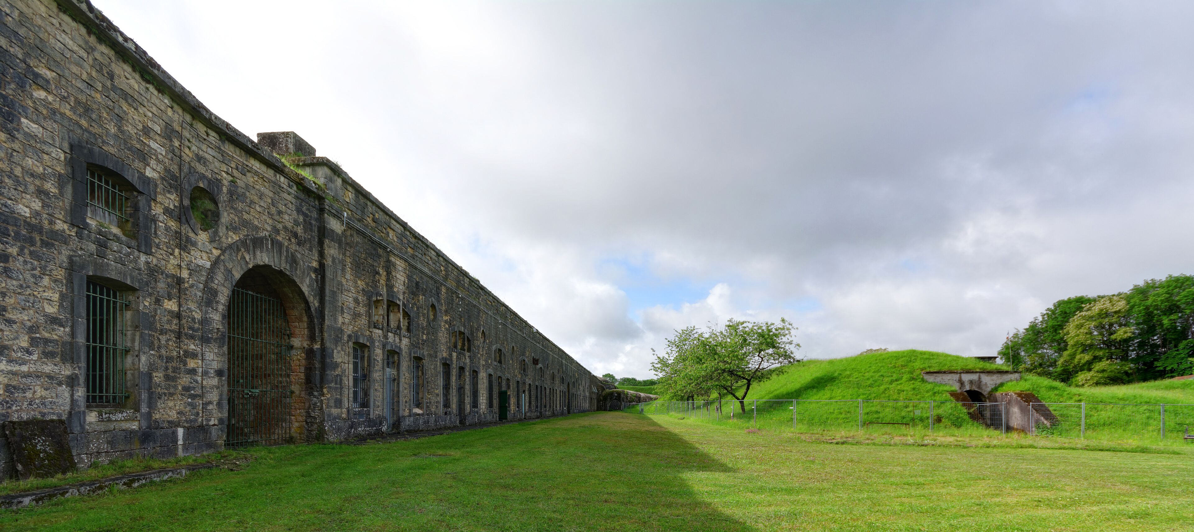 A historic stone building with arched windows and a grassy field.