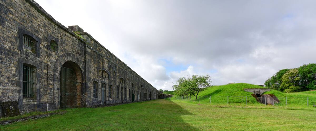 A historic stone building with arched windows and a grassy field.