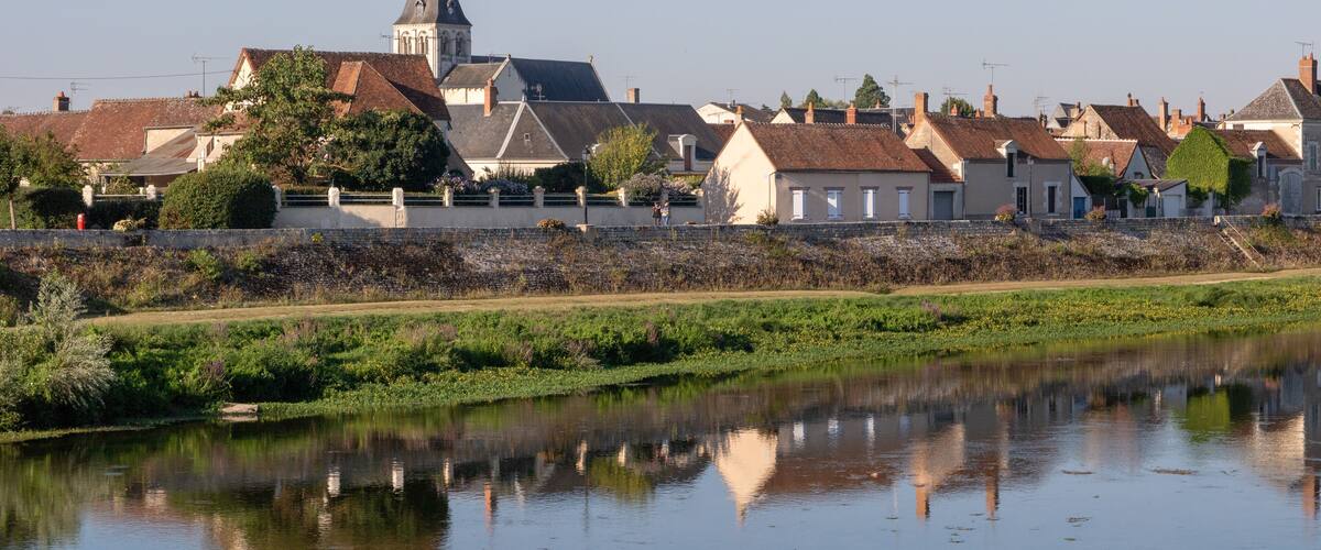 A river with houses and a church with a tall steeple.