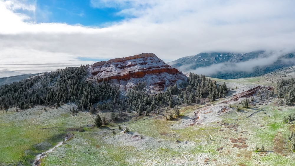 A mountain landscape with a prominent peak, dense forest, and a valley.
