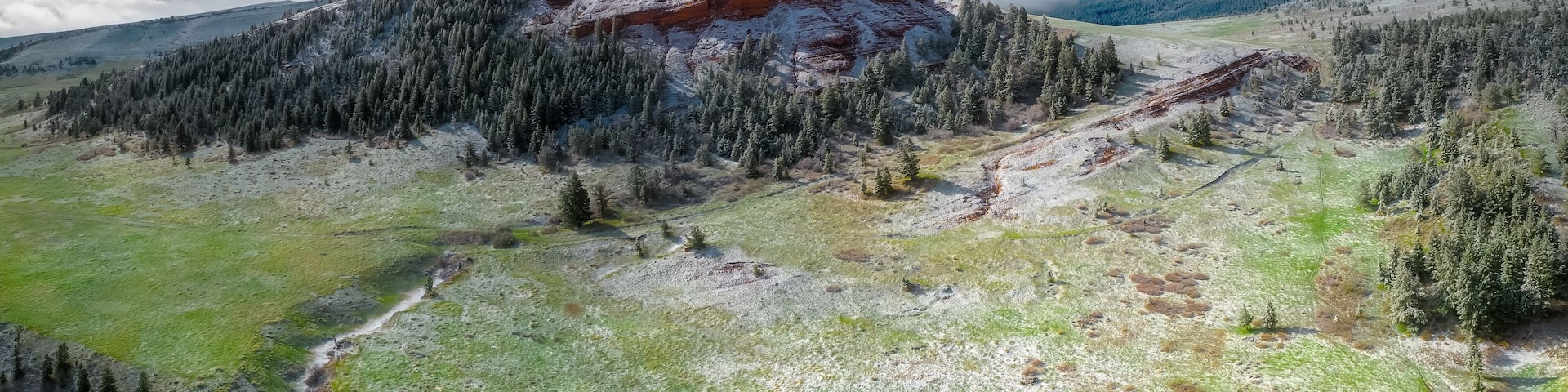 A mountain landscape with a prominent peak, dense forest, and a valley.