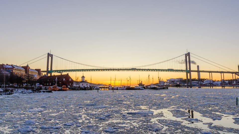 A frozen river with a bridge in the background.