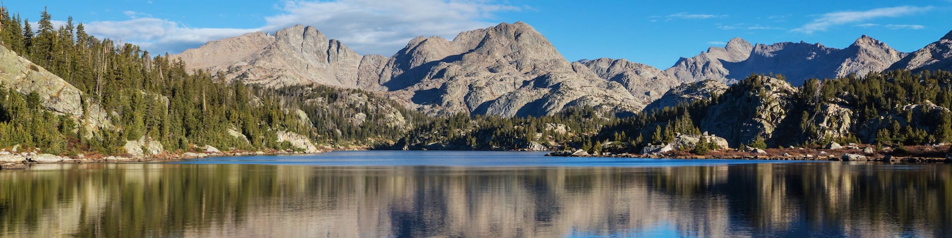 A mountain lake with rocky mountains and dense forests.