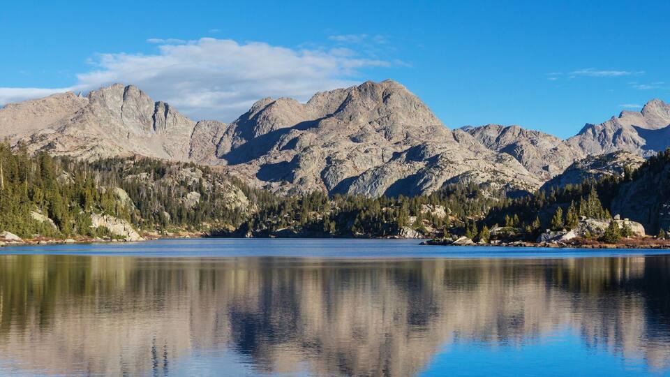 A mountain lake with rocky mountains and dense forests.