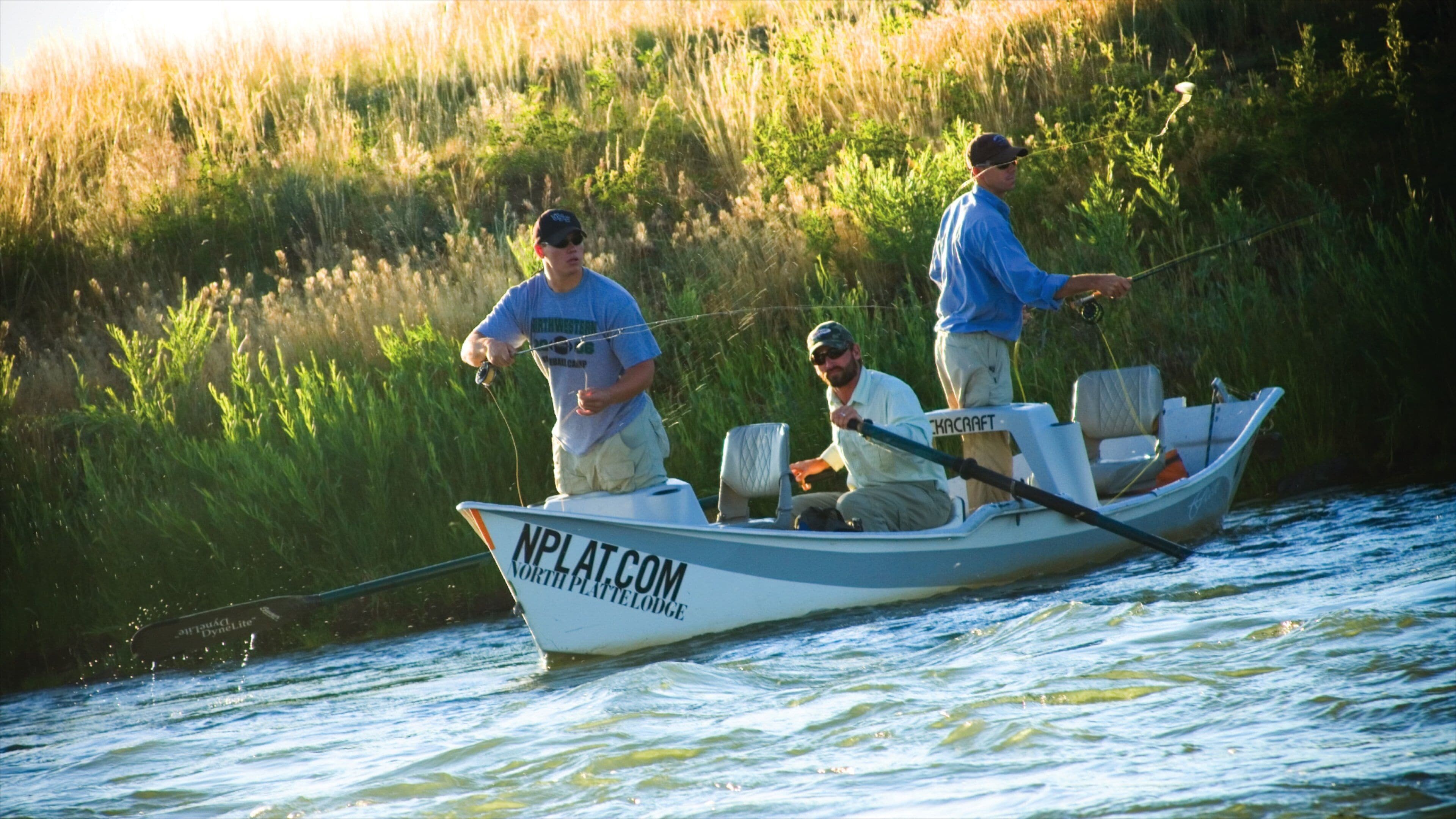 A boat on a river with tall grass on the banks.