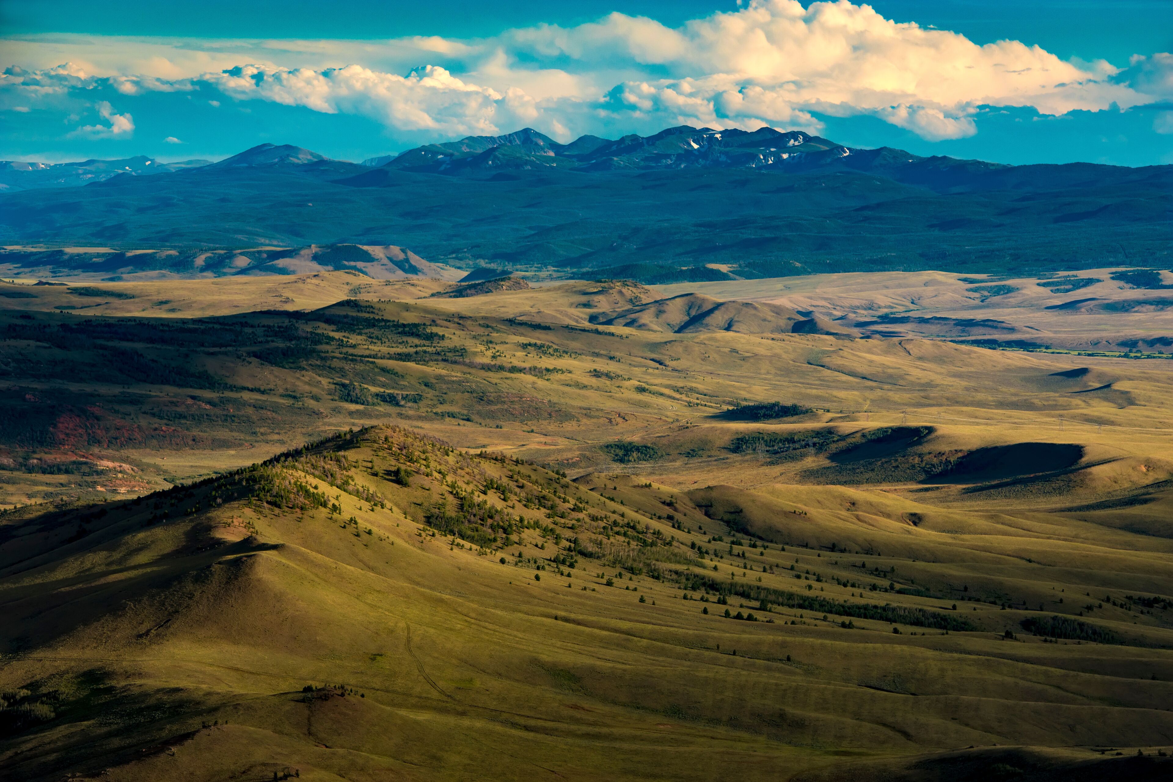 Paisagem montanhosa com colinas ondulantes e céu claro.