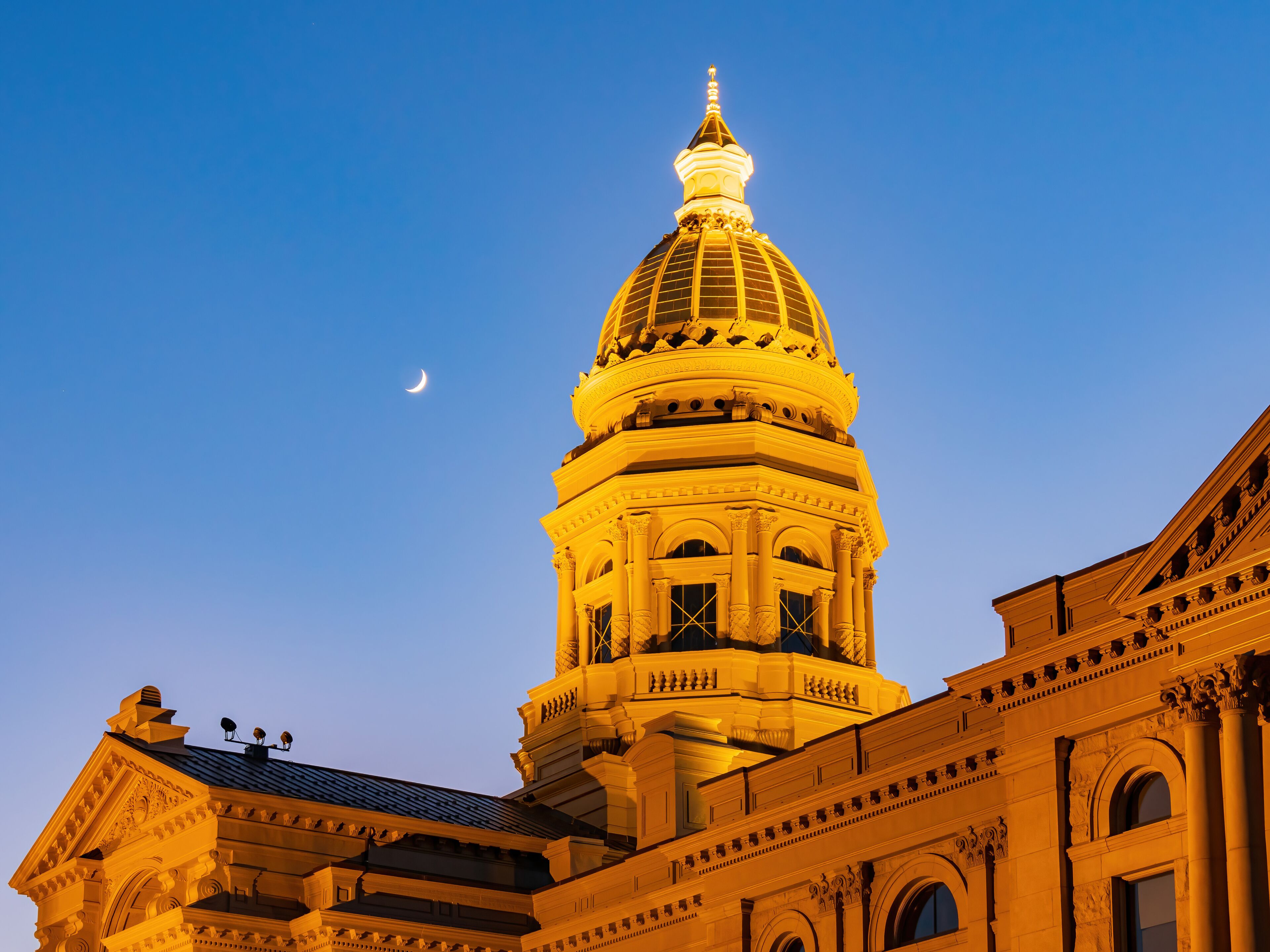 A grand building with a large dome and a crescent moon in the sky.