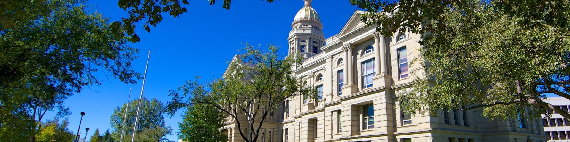 A historic building with a dome and columns, surrounded by lush green grass and trees.