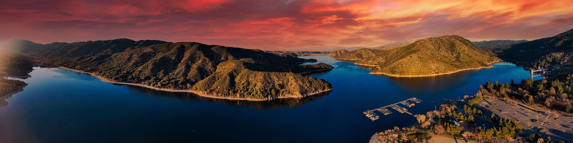 A mountainous landscape with a large lake, a small island, and a marina.