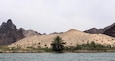 A desert landscape with a palm tree in the foreground and mountains in the background.