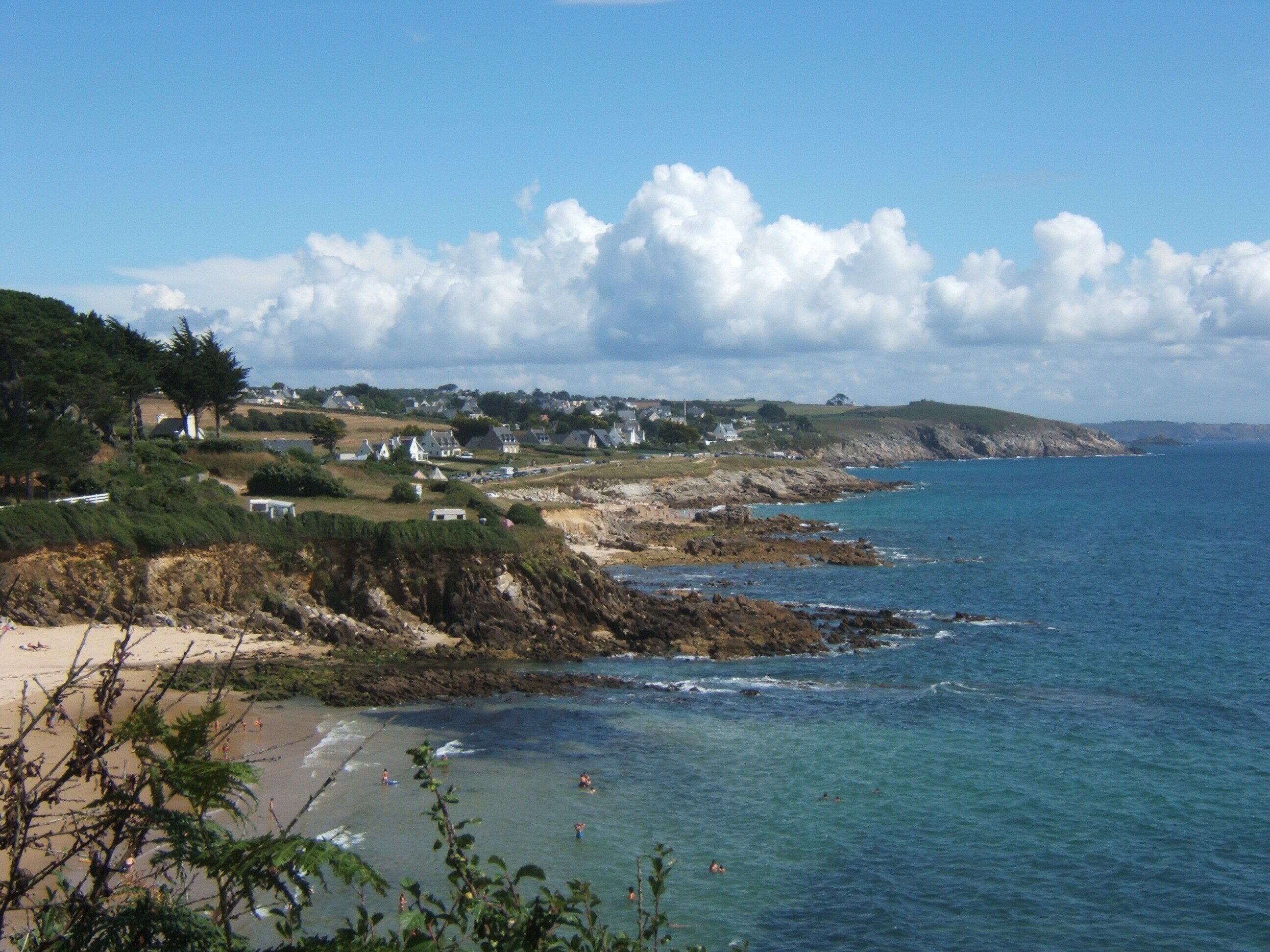 A coastal town with houses along the cliffside, a beach, and the ocean.