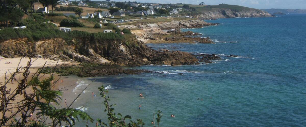 A coastal town with houses along the cliffside, a beach, and the ocean.