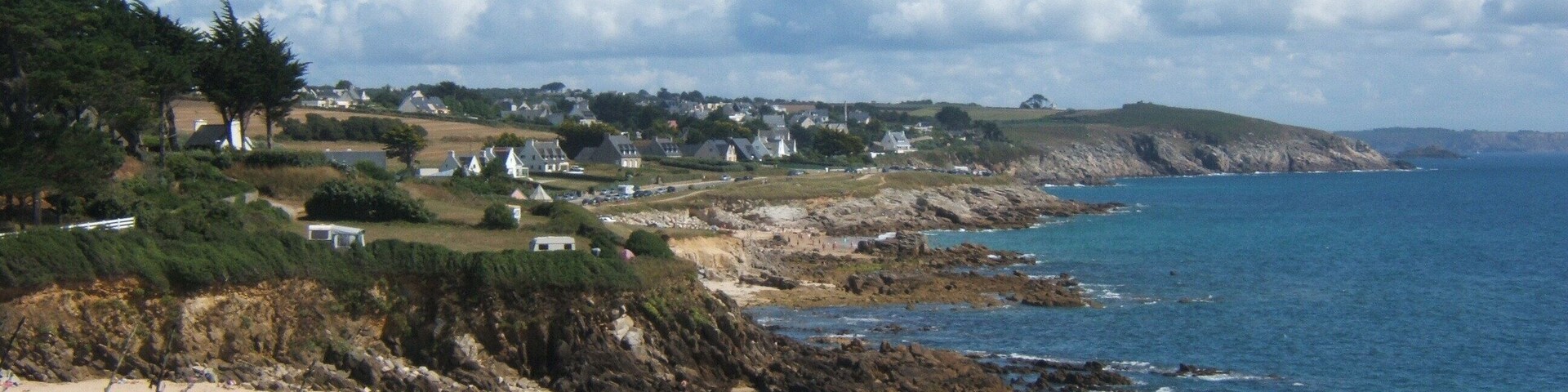 A coastal town with houses along the cliffside, a beach, and the ocean.