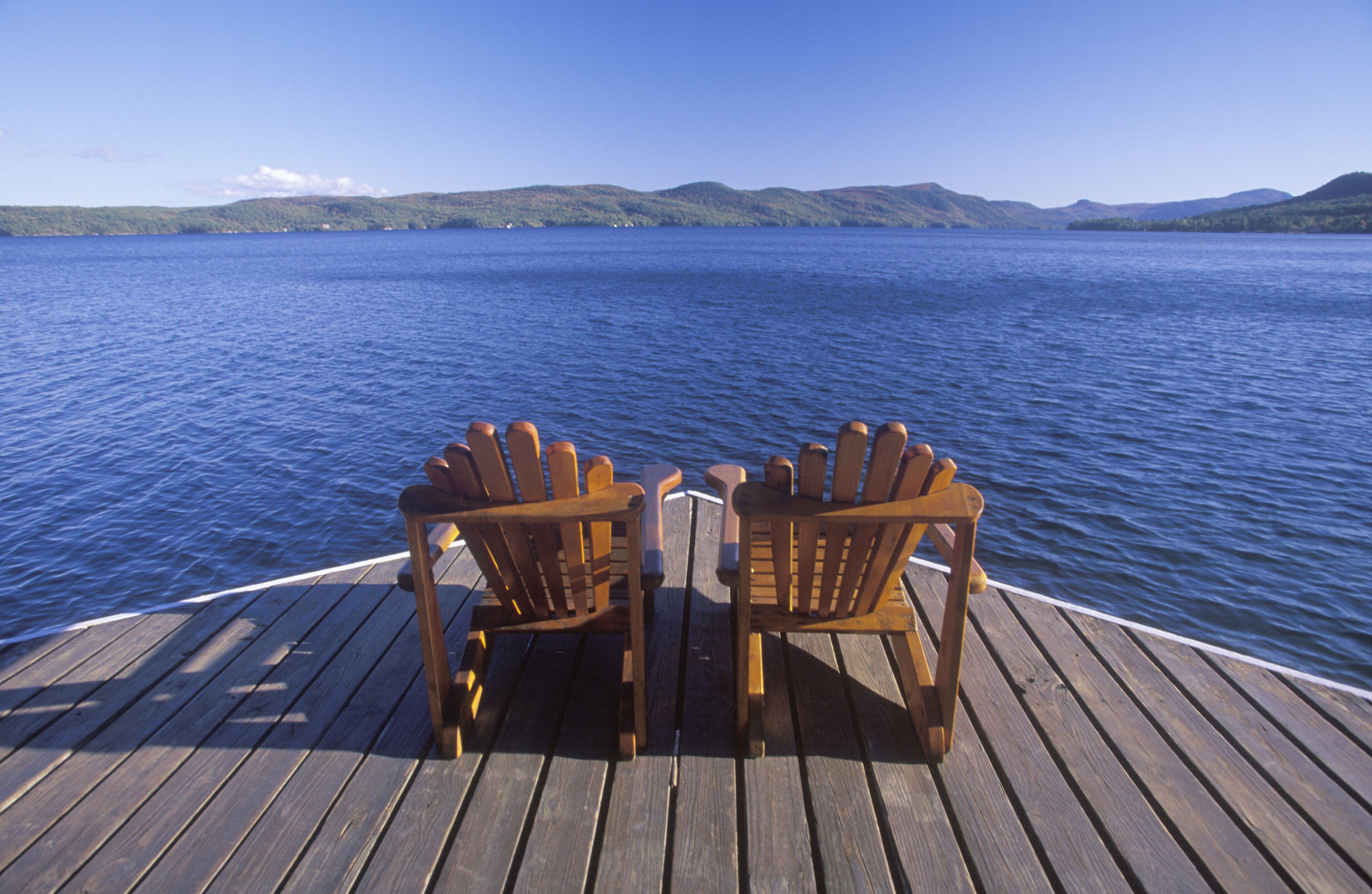 Two Adirondack chairs on a deck overlooking Lake George, NY
