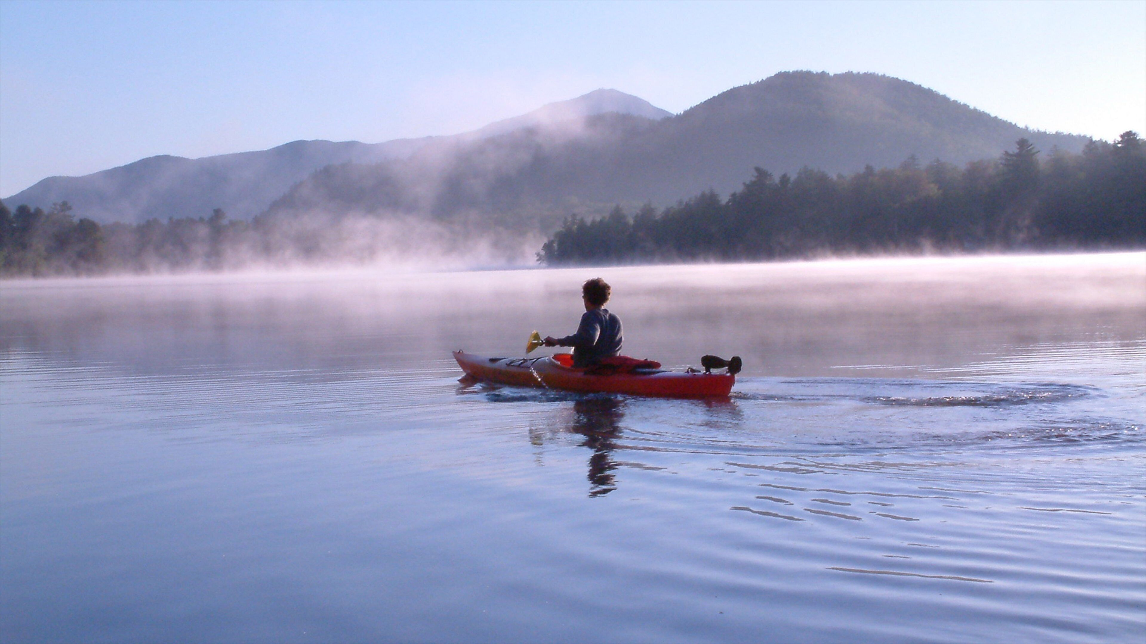 Lake Placid which includes mist or fog, a lake or waterhole and kayaking or canoeing