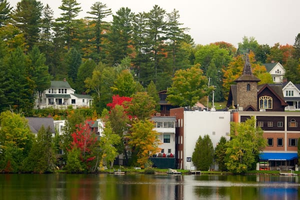 A lakeside town with autumn-colored trees, a variety of buildings including a church, and a dock with boats.